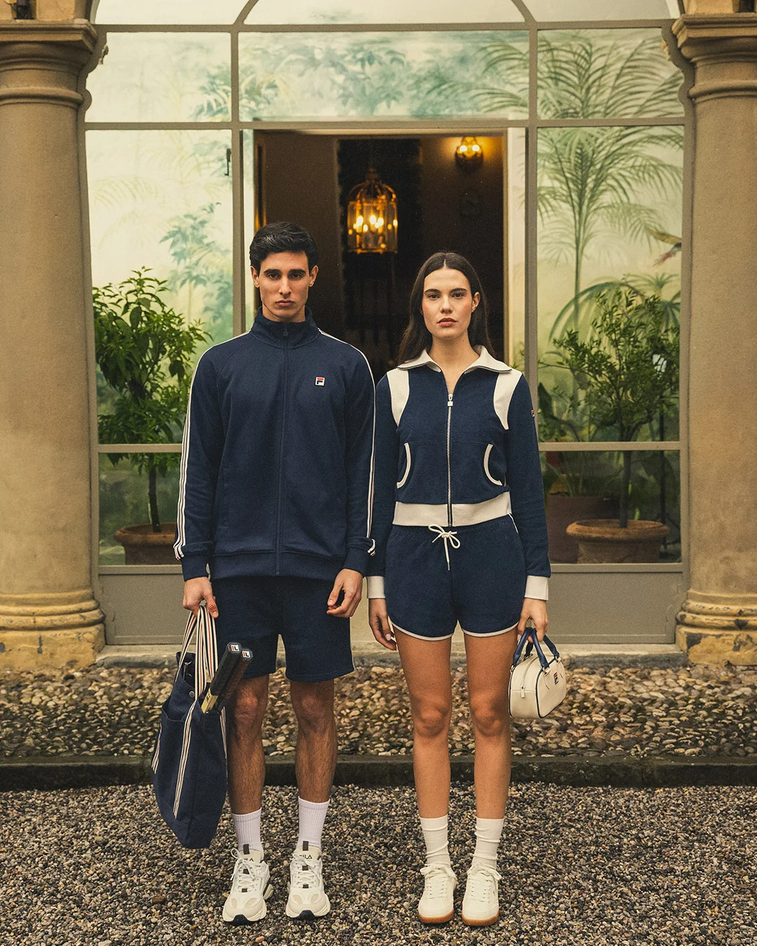 FILA Editorial — zwei Models in marineblauen Trainingsanzügen vor einem historischen Wintergarten